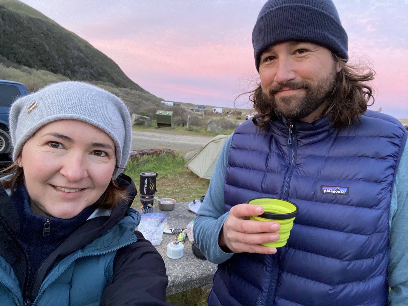Two backpackers at camp at Mattole with a pink sky over the King Range at dusk