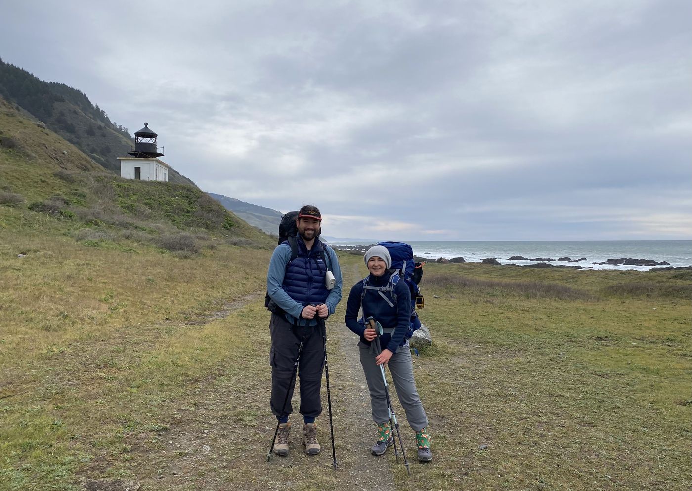 Two backpackers standing in front of the Punta Gorda Lighthouse on the Lost Coast