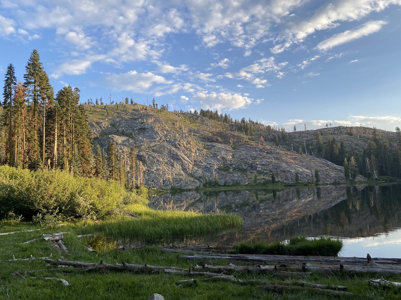 A granite dome reflected in the still water of Milk Lake in golden evening light