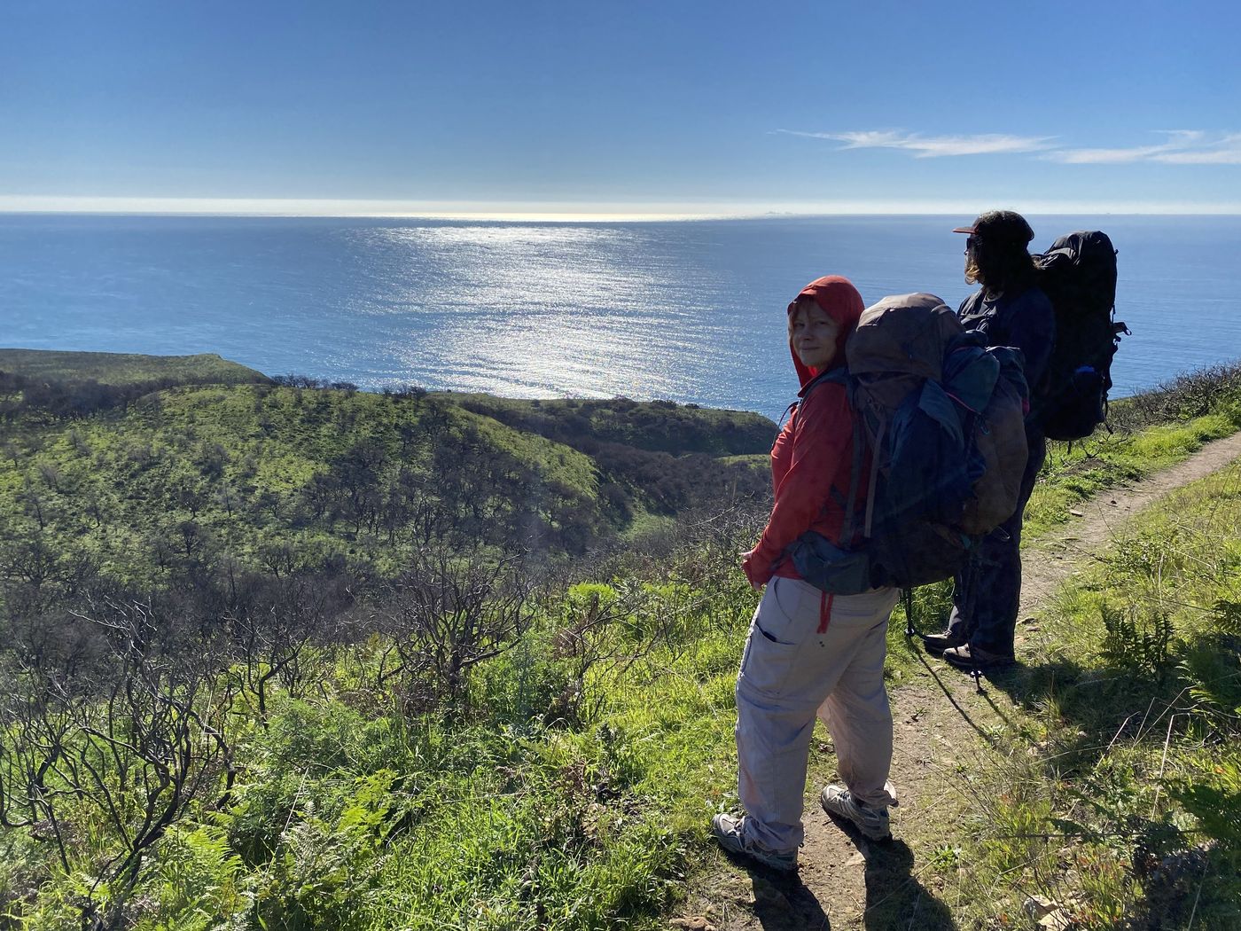 A backpacker on a grassy bluff trail high above the Pacific at Point Reyes