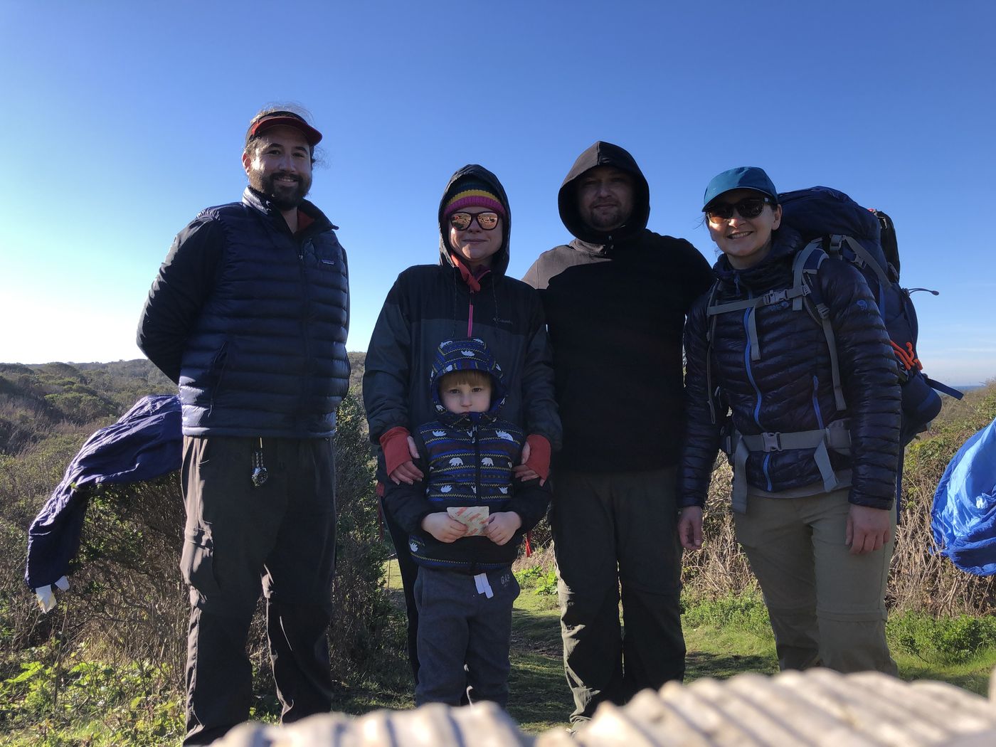 The whole group, four adults and a small child, posing together on a bright clear morning