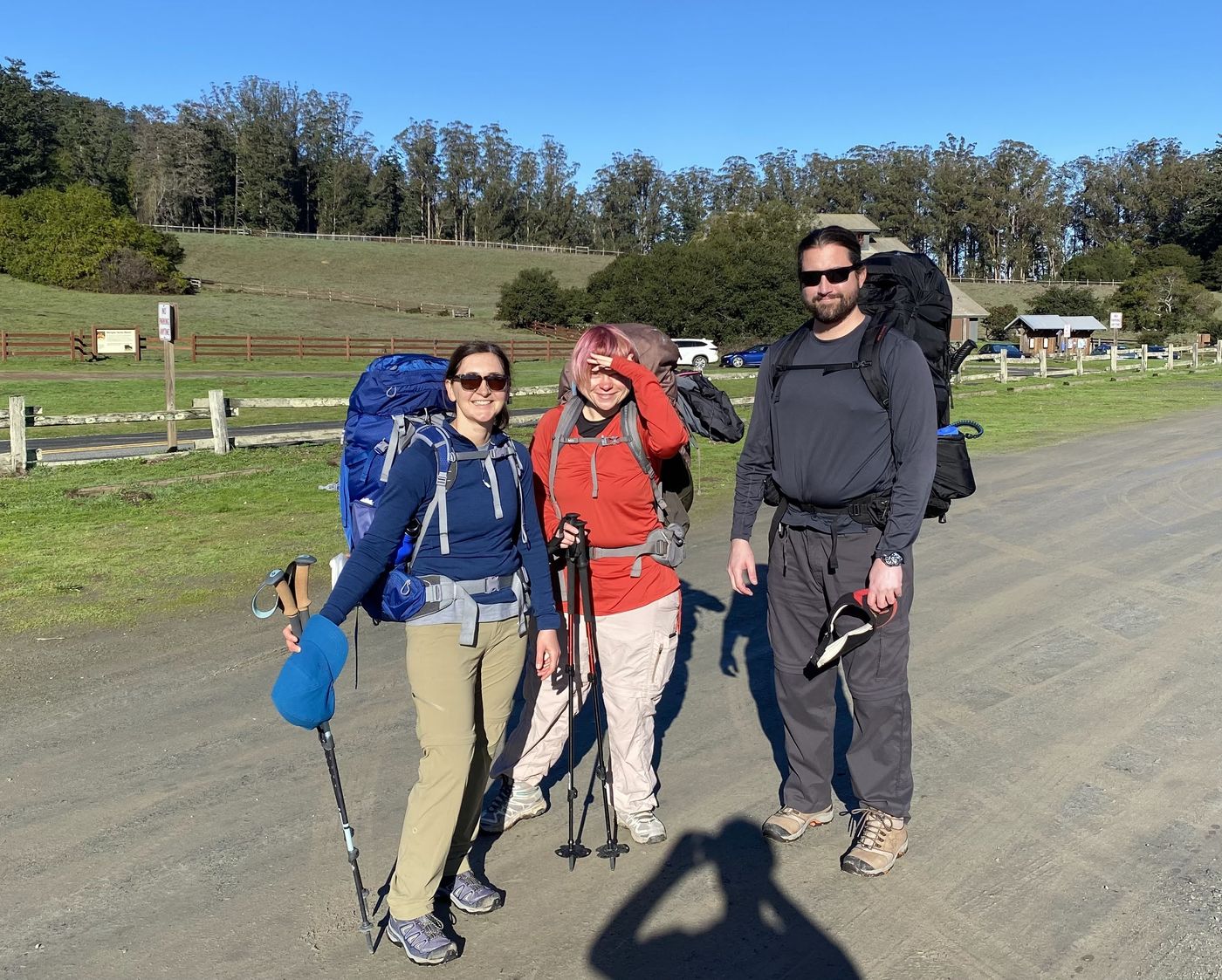 Three backpackers with full packs at the Bear Valley trailhead in Point Reyes