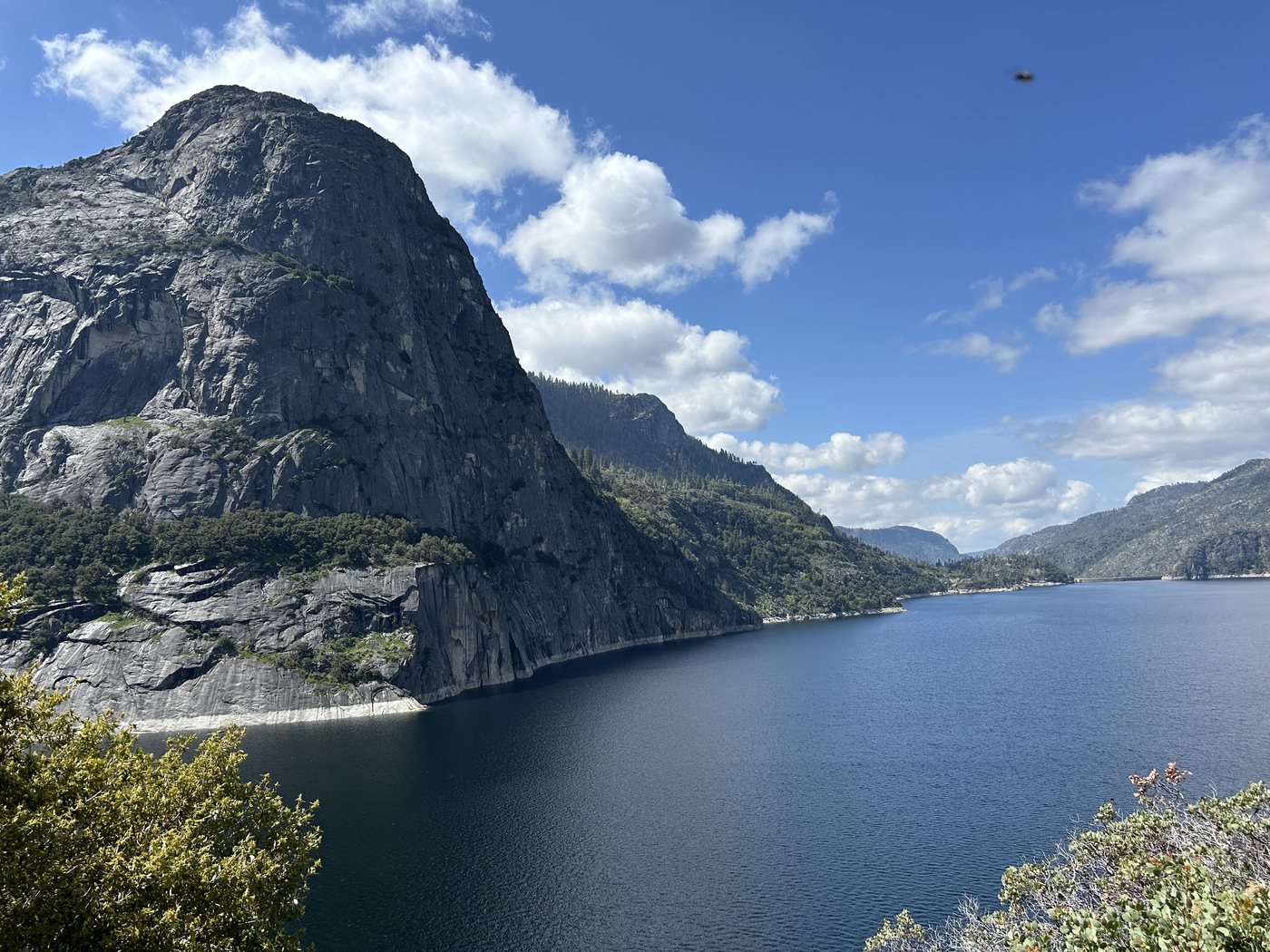 Kolana Rock rising as a rounded grey dome above the deep blue reservoir under a sky of bright cumulus