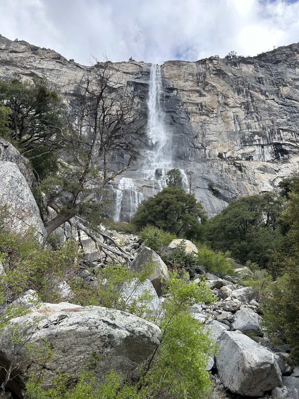 Tueeulala Falls dropping in a single narrow ribbon down a sheer granite wall and spreading into a wide fan over slabs above a boulder field