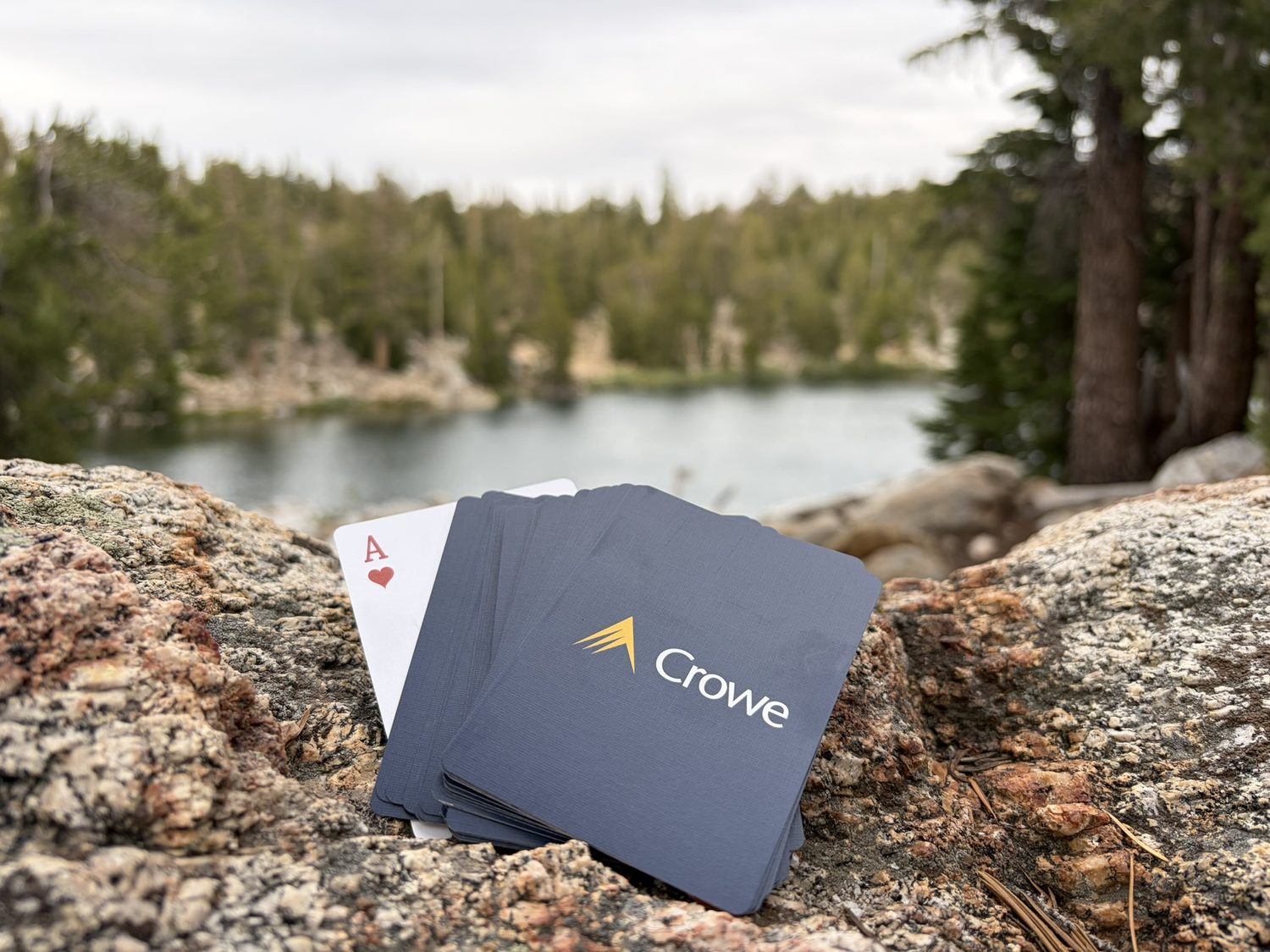 Playing cards laid out on granite at the edge of an alpine lake in the evening