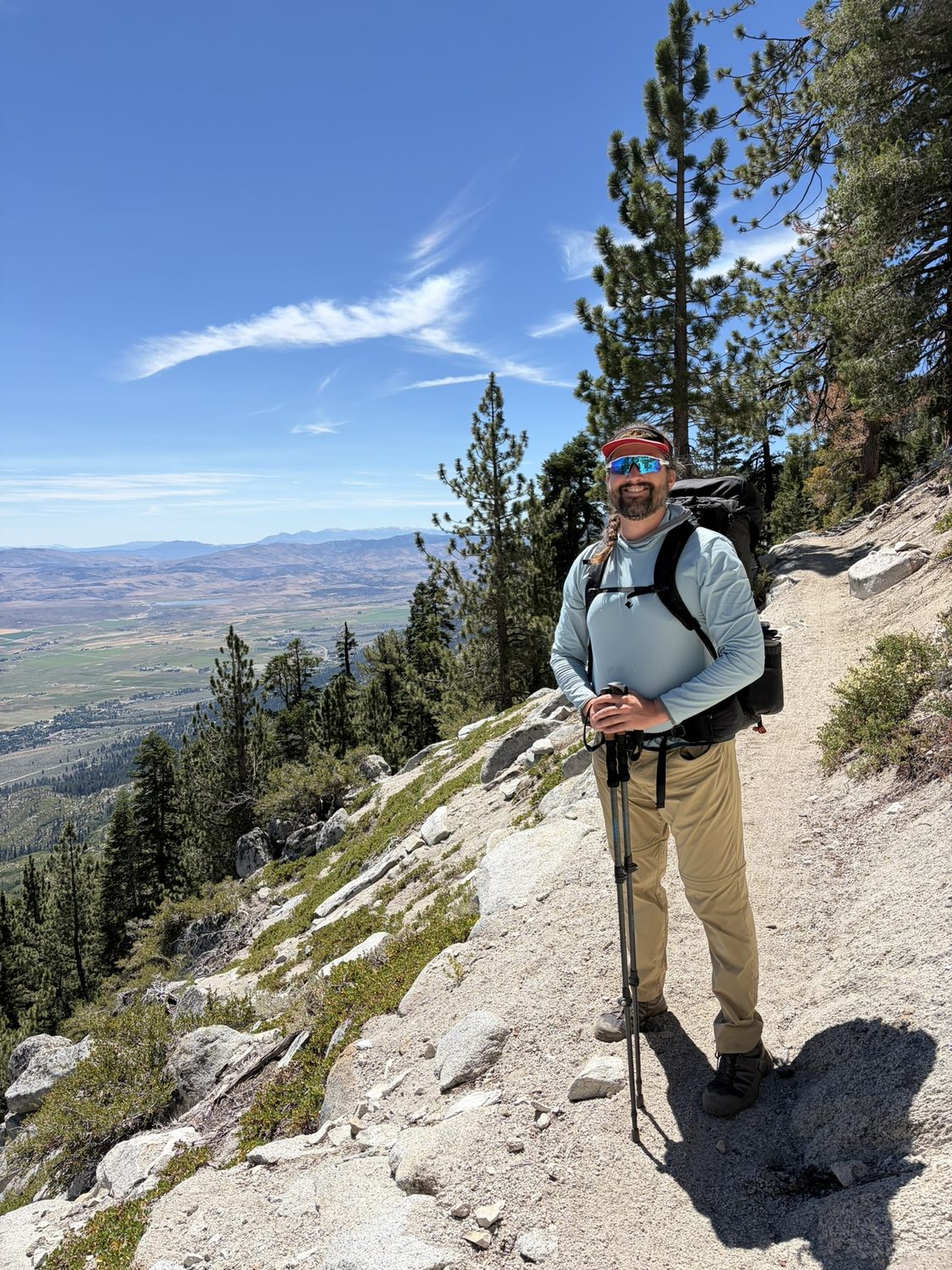 A hiker climbing a rocky alpine trail toward high granite country under blue sky