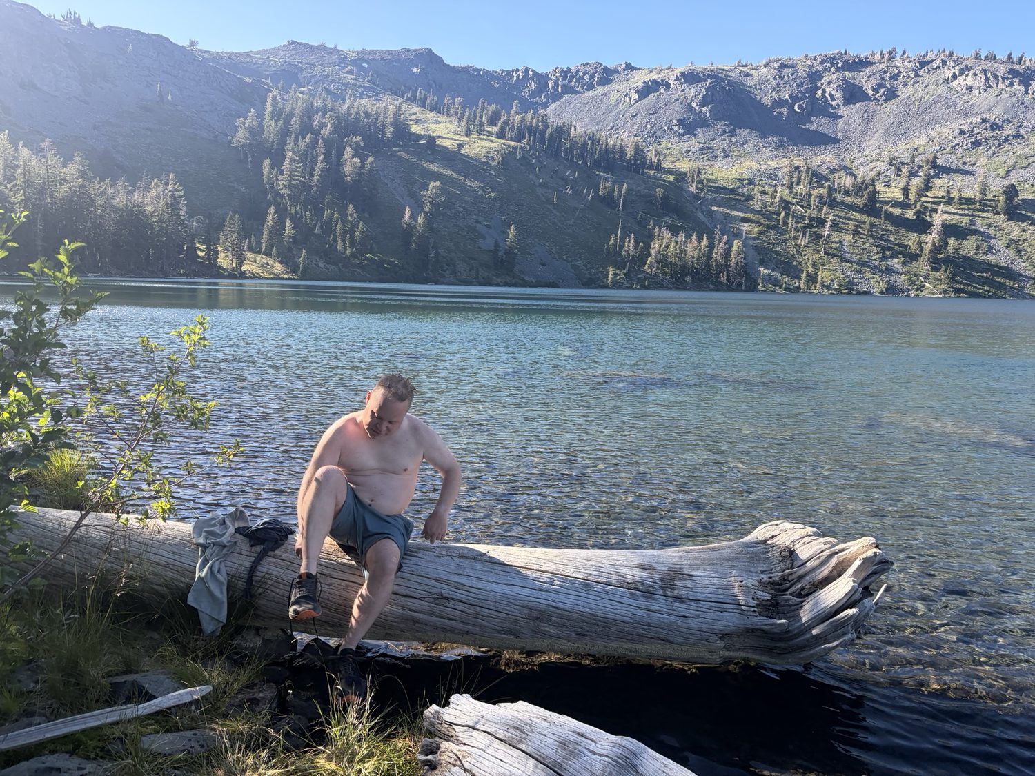 A person cooling off at a granite-lined alpine lake in Desolation Wilderness in warm light