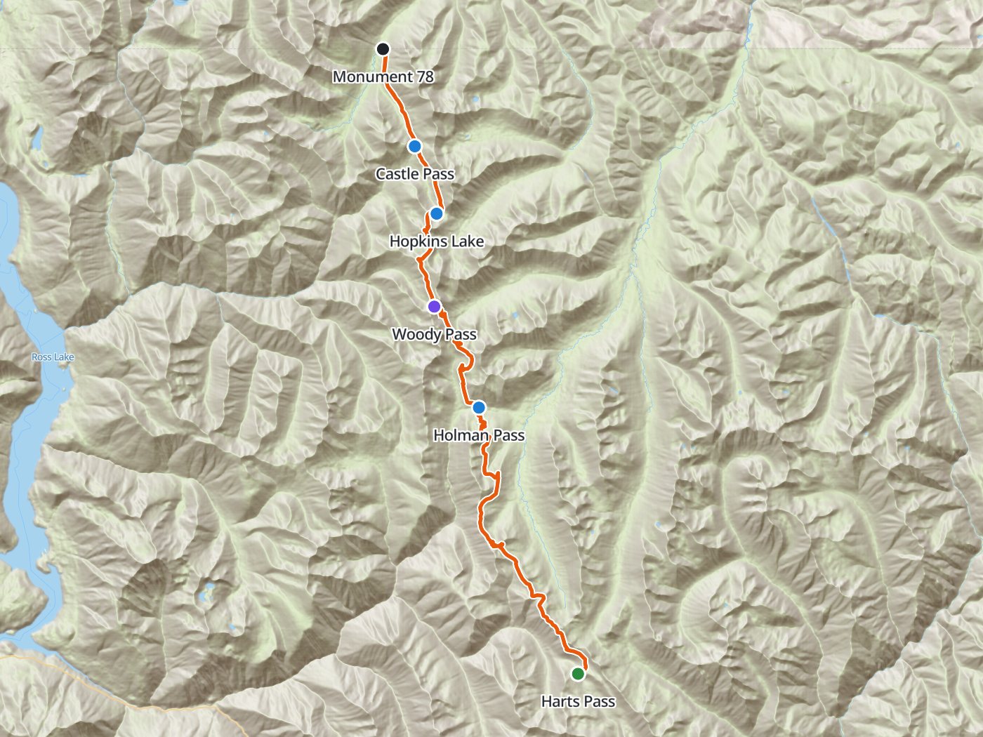 Topographic map of the northern Pacific Crest Trail, with the route drawn in orange from Harts Pass north along the crest past Holman Pass, Woody Pass, Hopkins Lake, and Castle Pass to Monument 78 on the Canadian border